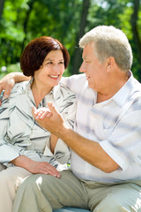 Happy senior couple embracing outdoors. Focus on woman