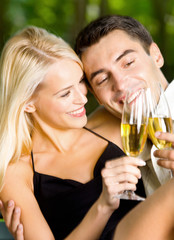 Young couple celebrating with champagne, outdoors