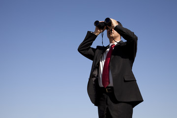 Businessman looking through binoculars