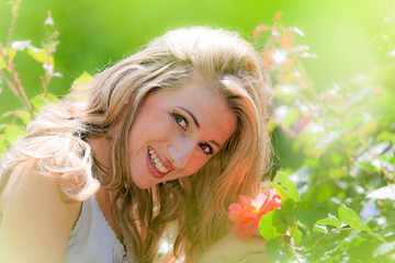Frau riecht an einer Rose im Garten