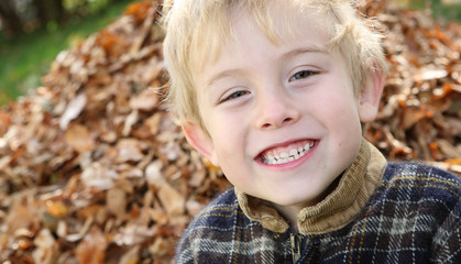 Smiling boy in front of a pile of leaves