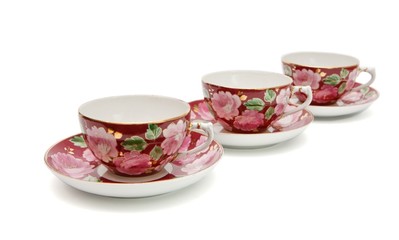 Three tea cups with saucers painted with floral pattern isolated
