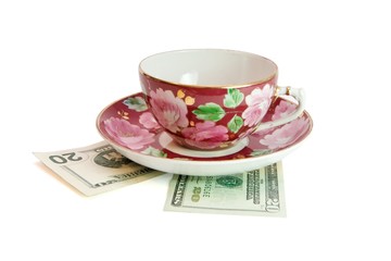 Tea cup and saucer on twenty dollar bills isolated