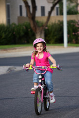 A little girl riding her bike in the neighborhood.