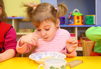 Little girl eats in kindergarten