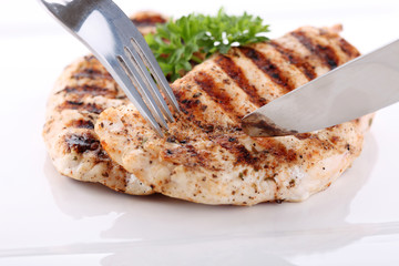 Grilled chicken breasts on a plate with fresh vegetables