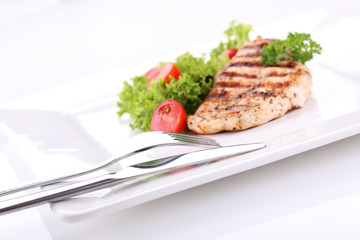 Grilled chicken breasts on a plate with fresh vegetables