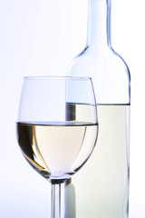 Glas Weißwein mit Flasche im Hintergrund