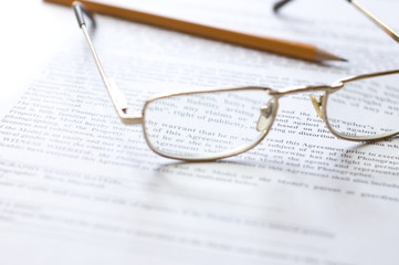 Close-up of document, eyeglasses and pencil.
