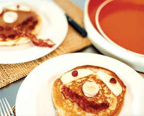 plates of pancakes with faces on them in bacon