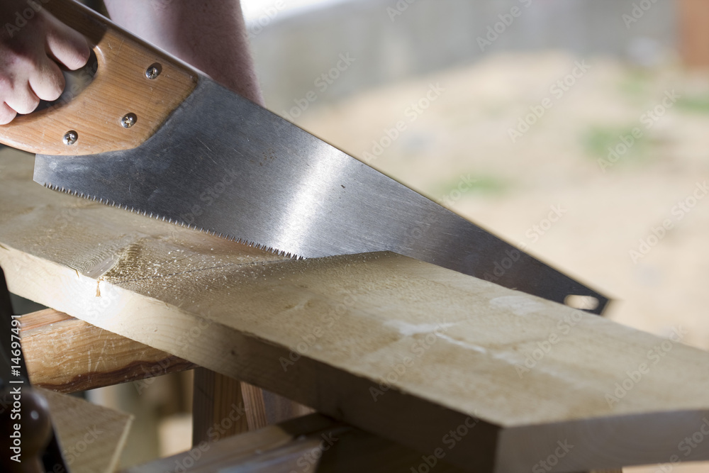 Wall mural carpenter cuts a plank with a saw