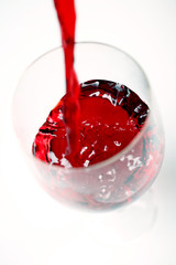 red wine being poured into a glass on white background