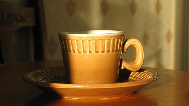Cup with hot coffee on saucer. Time lapse. Moving shadow.