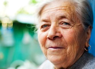 Face closeup of smiling happy elderly woman outdoors