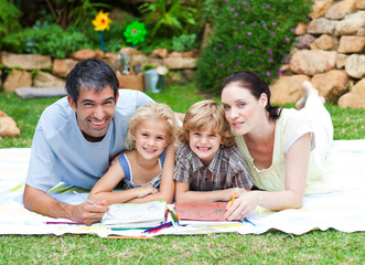 Happy family painting in a park smiling at the camera