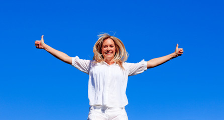 Young woman jumping against blue sky