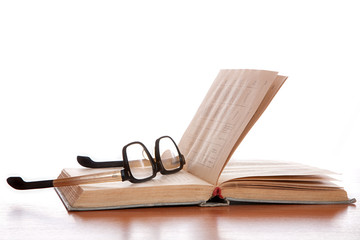 Old glasses and the old book laying on a table