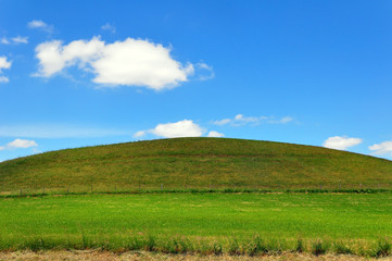 Obraz premium A hill with a green meadow and blue sky