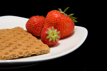 white plate with trawberry and cracker