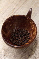 black peppercorn in coconut bowl on old wooden table