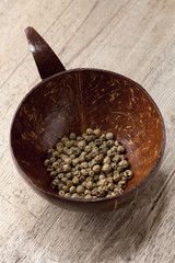 green peppercorn in coconut bowl on old wooden table