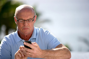 Homme senior composant un numéro de téléphone