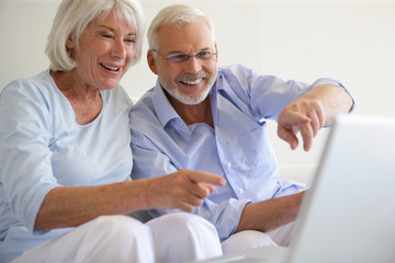 Couple de seniors souriants devant une webcam