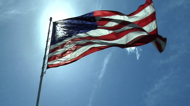 American US flag waving in the wind with sunrays