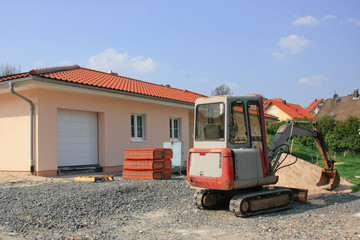 Kleinbagger vor einem Bungalow