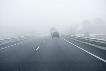 Foggy gray road, cars driving into the fog