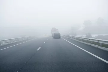 Photo sur Plexiglas Hiver Foggy gray road, cars driving into the fog