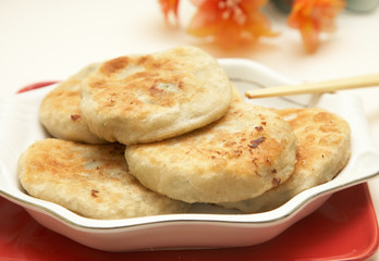 Chopsticks holding chinese traditional meat pie.