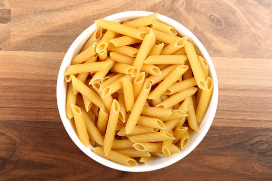 Top view of dry penne rigate in white ceramic bowl