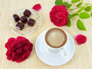 Fototapeta na wymiar Filiżanka kawy z śmietany, cukierki czekoladowe i czerwona róża