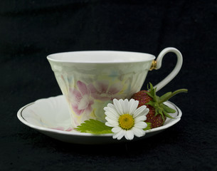 Cup, chamomile and strawberry on black