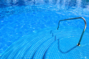 Pool with blue water stairs rail at daylight