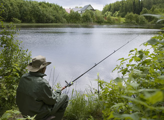 Seated senior man fishing off a shoreline
