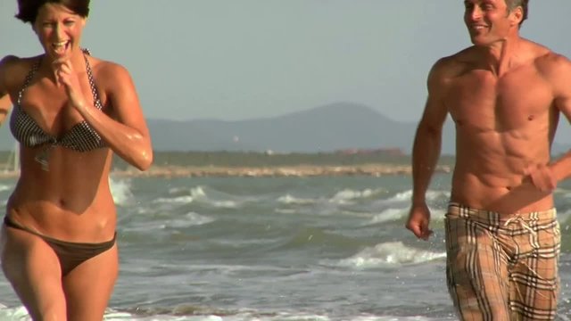 Uomo insegue per gioco una donna al mare di corsa