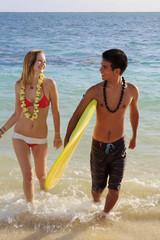 hawaiian beach boy teaches surfing to a blond tourist