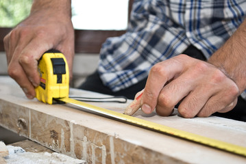 A woodworker measures the mark for his cut