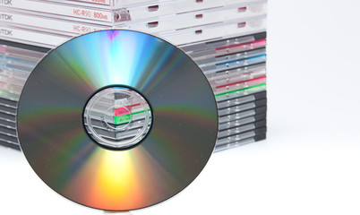 a blank dvd or cd with stack of empty cd cases on background