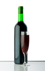 Bottle and wine glass on reflective background