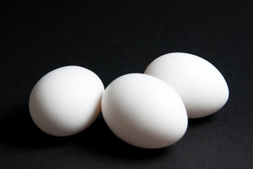 Three White Eggs on Black Background