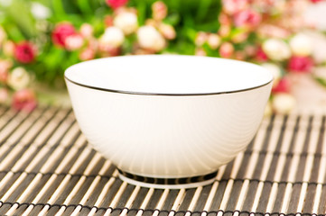 Traditional asian bowl and flowers at background