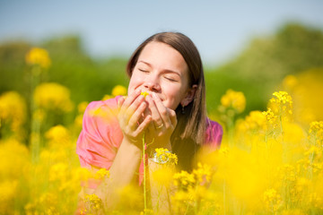 Pretty smiling girl relaxing on meadow full of yellow flowers. S