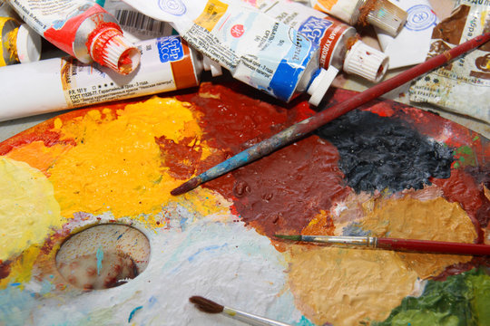 Brushes lay on an art palette in bright paints
