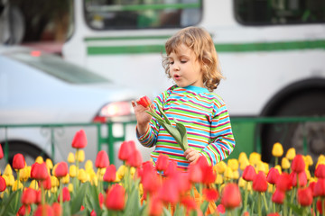 Little girl in striped t-shirt and tulips on street