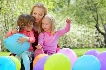 Mother, daughters and balloons in garden in spring