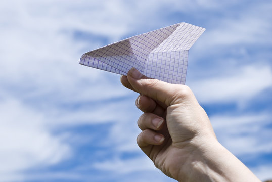 Hand holding a paper airplane on  sky background
