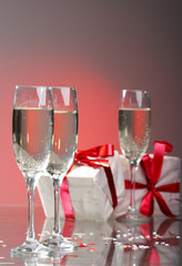 Glasses of champagne, gifts with red tapes and bows